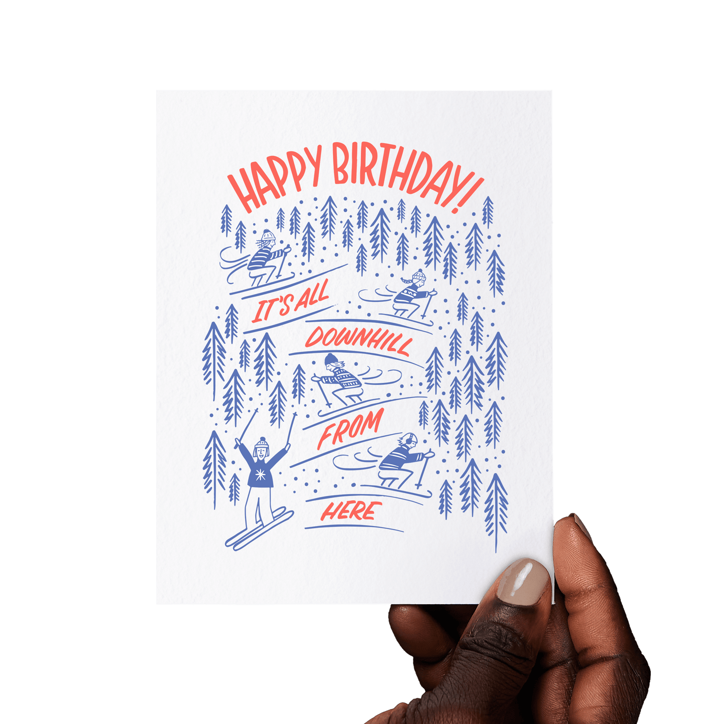 Hand holding a ski-themed birthday card with 'It’s All Downhill From Here!' and playful skiing illustrations.