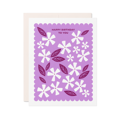 Letterpress birthday card with white floral illustrations, berry-toned leaves, and a purple scalloped border reading “Happy Birthday to You.