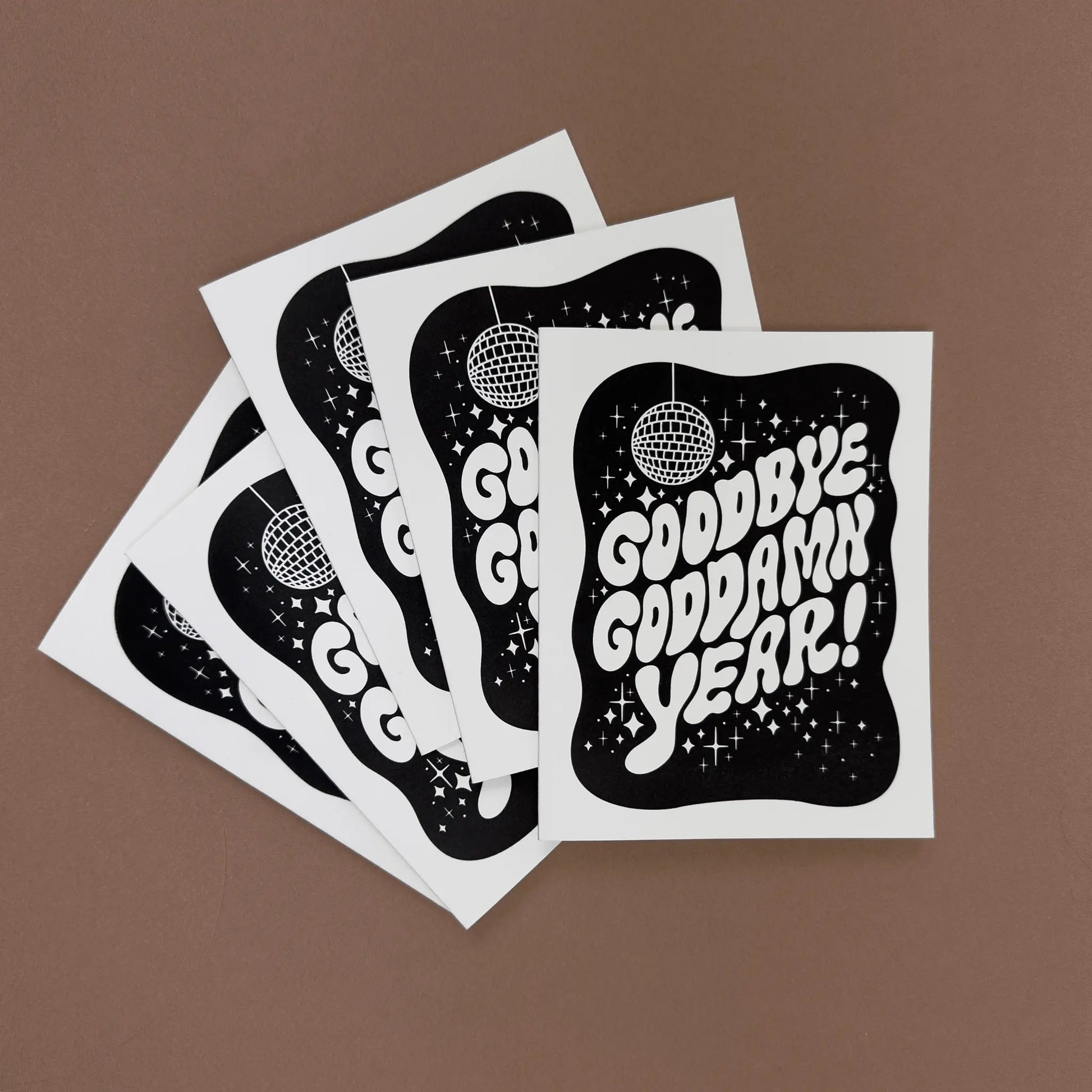 Stack of New Year cards with 'Goodbye goddamn year!' in bold bubble hand-lettering and disco ball design.