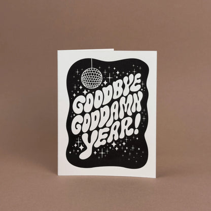 New Year card with 'Goodbye goddamn year!' displayed upright on a light brown background.