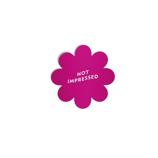 Bright pink flower-shaped sticker with ‘Not Impressed’ in white lettering, featuring a silky matte mirror finish.
